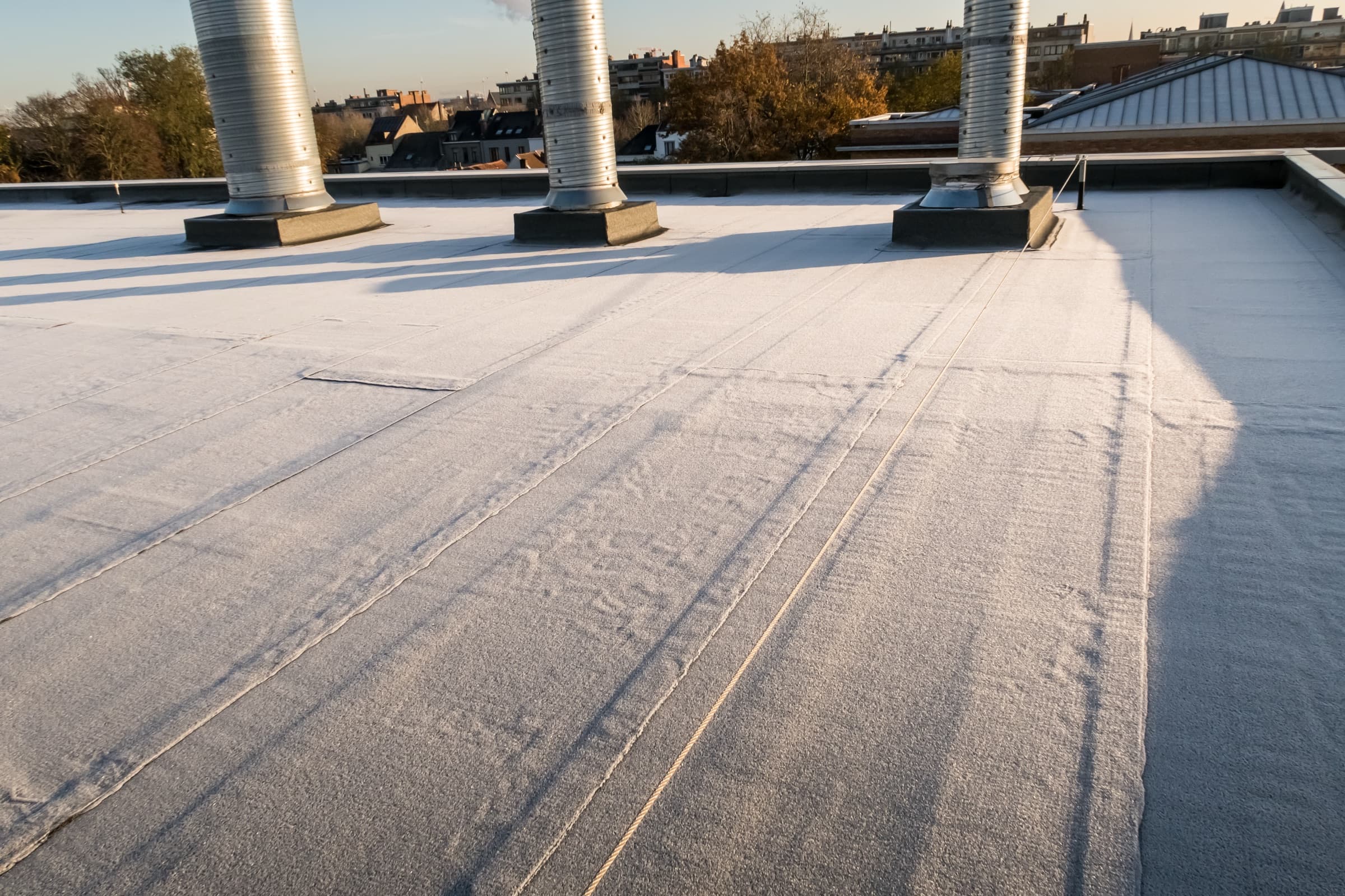 Flat membrane roof with vent stack penetrations and seams visible across the surface