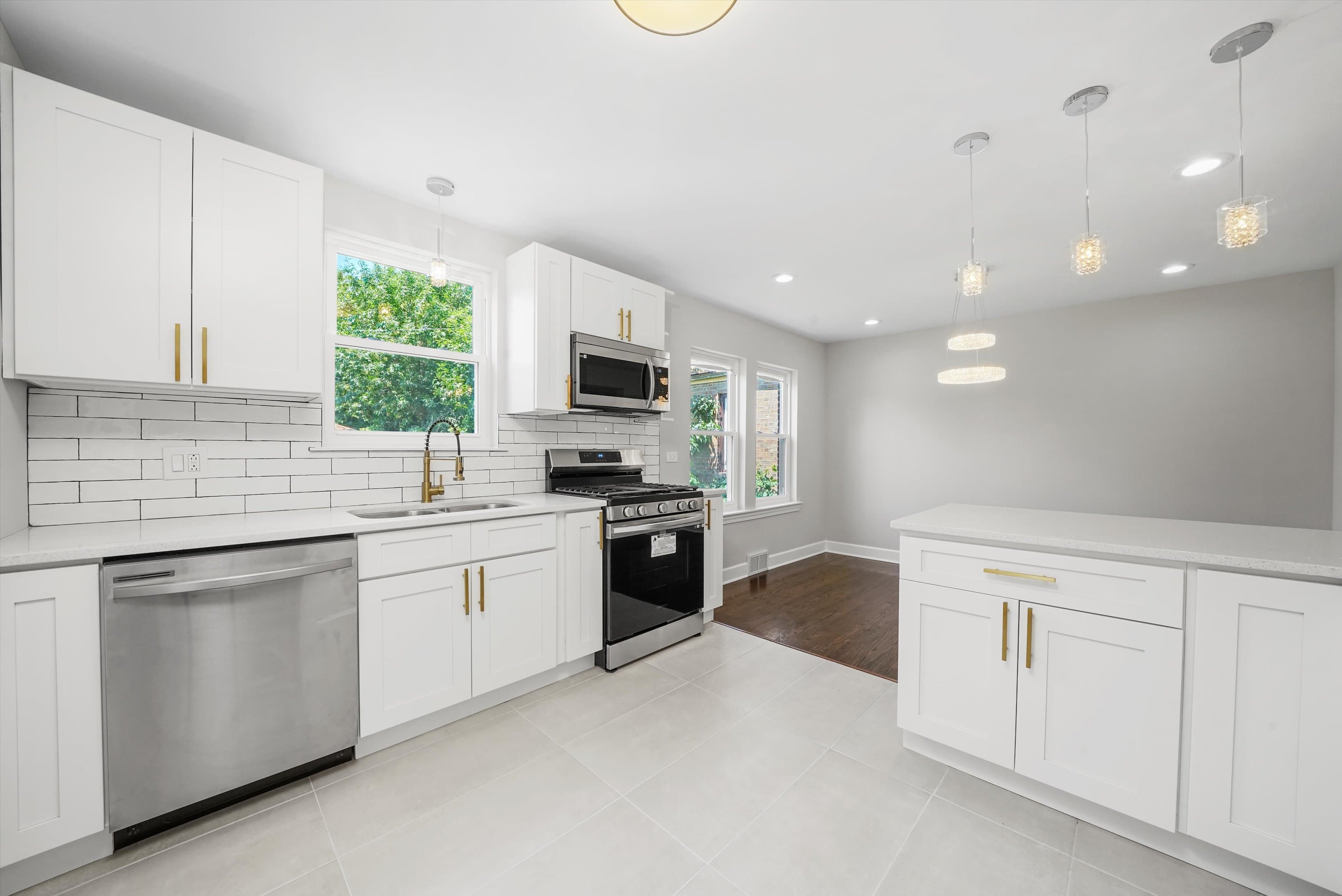 A fully renovated kitchen with white shaker cabinets and subway tile backsplash
