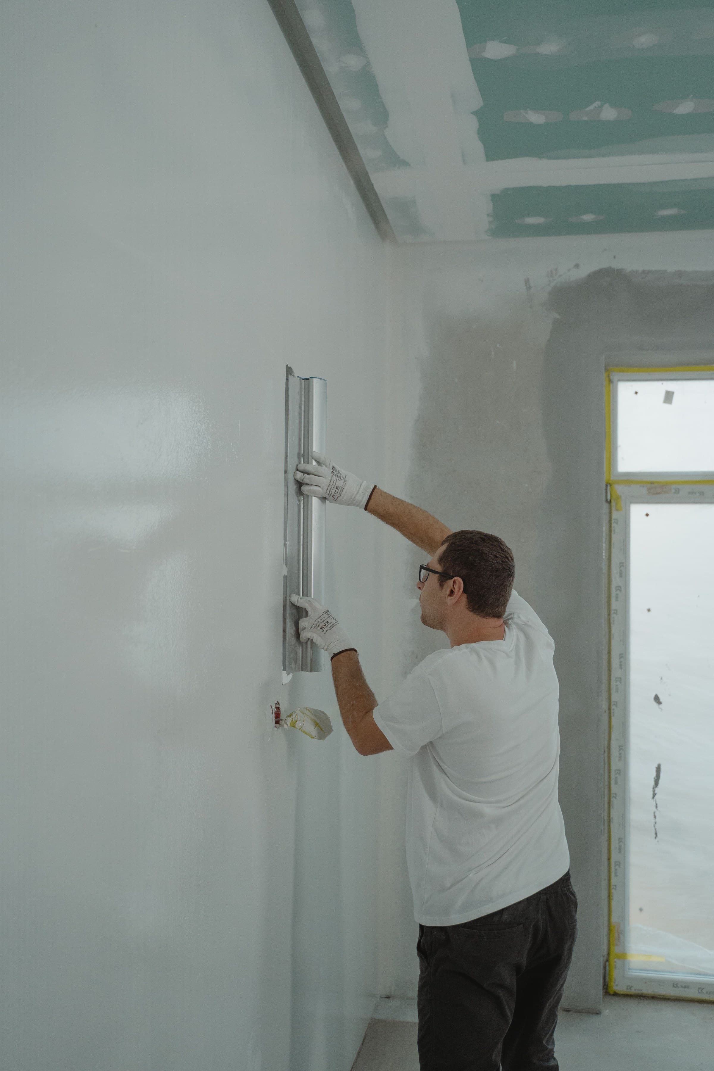 A contractor finishing drywall during a commercial interior renovation