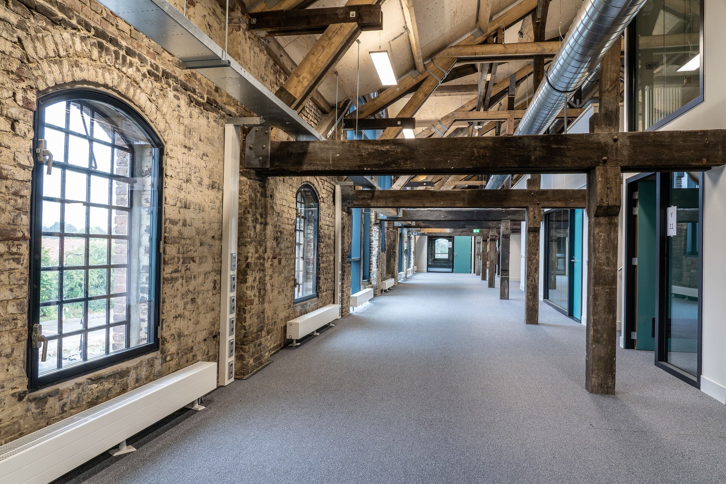 A renovated commercial office corridor with exposed brick and timber beams