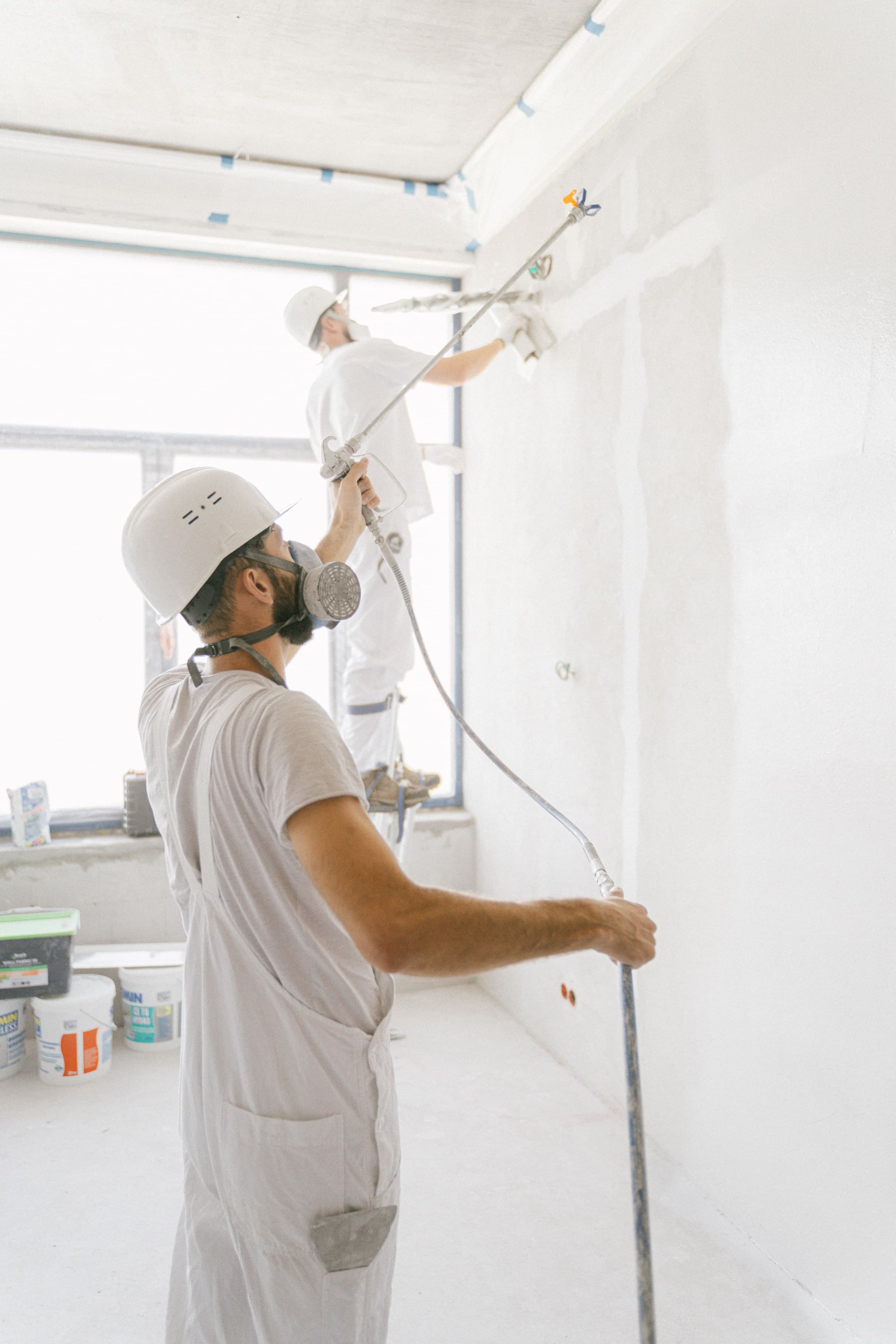 Contractors spraying wall texture during a commercial interior renovation