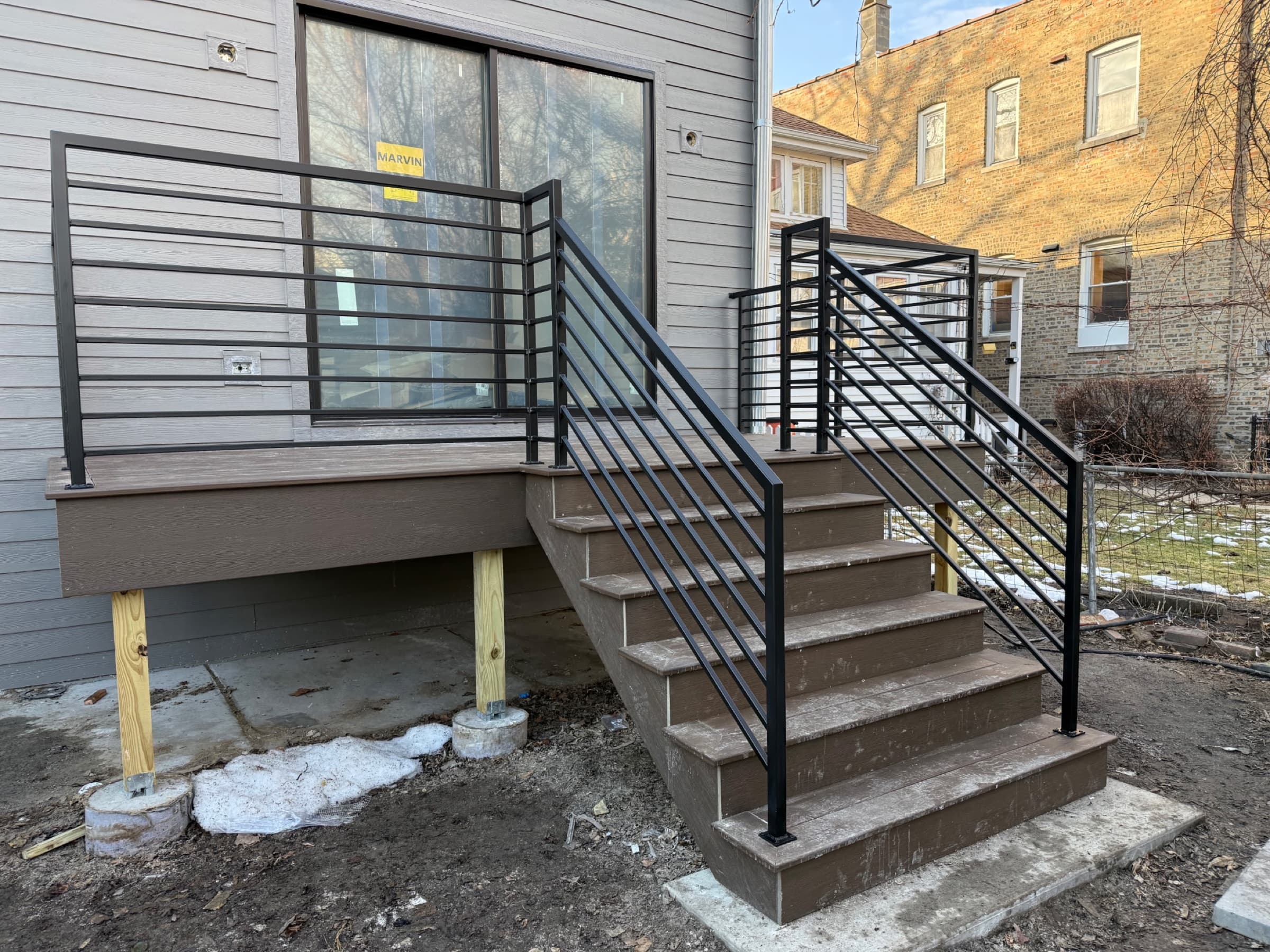 New composite deck and stairs with a black horizontal-bar steel railing at a sliding glass door