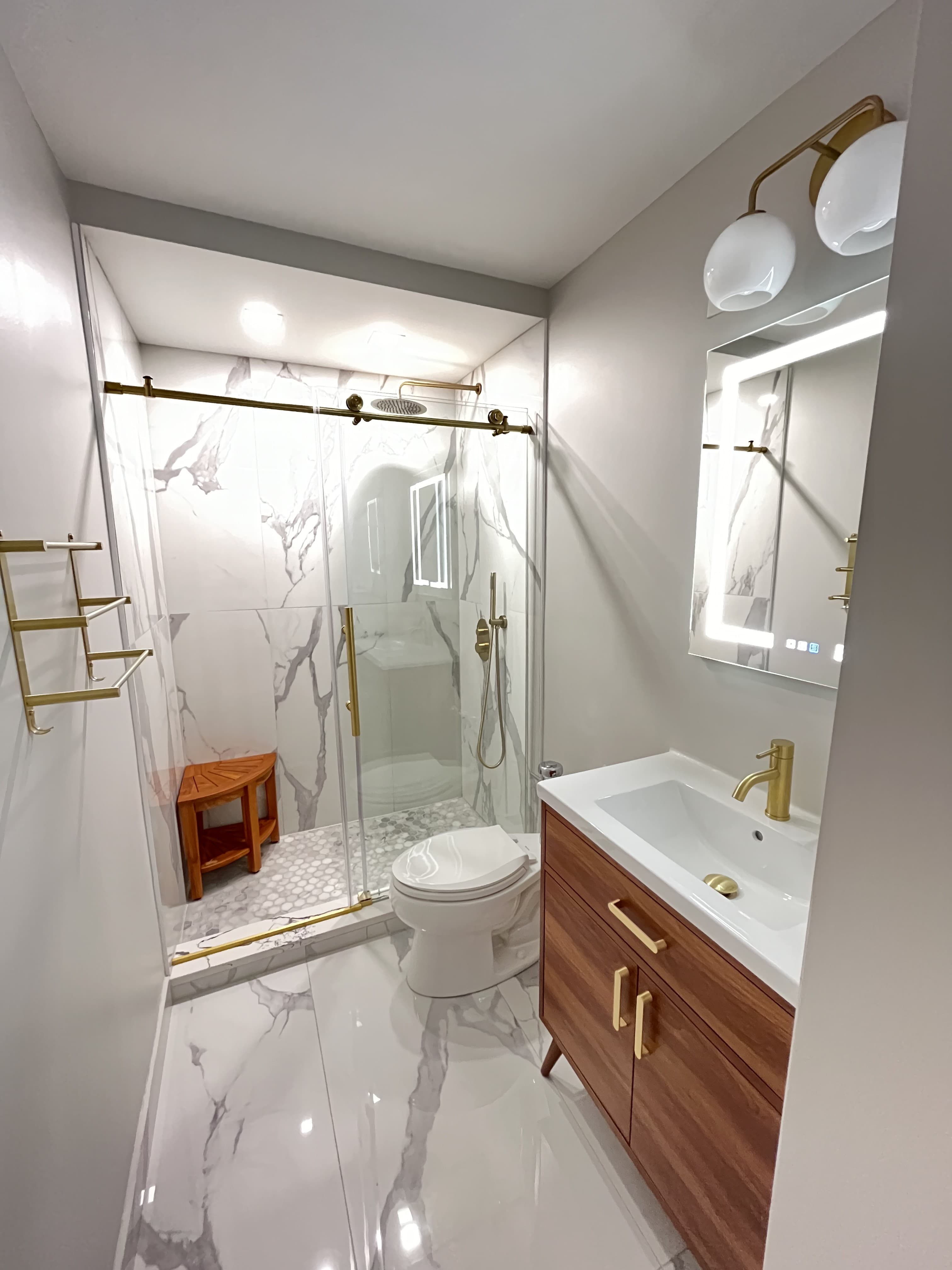 A renovated bathroom with a marble-tiled walk-in shower