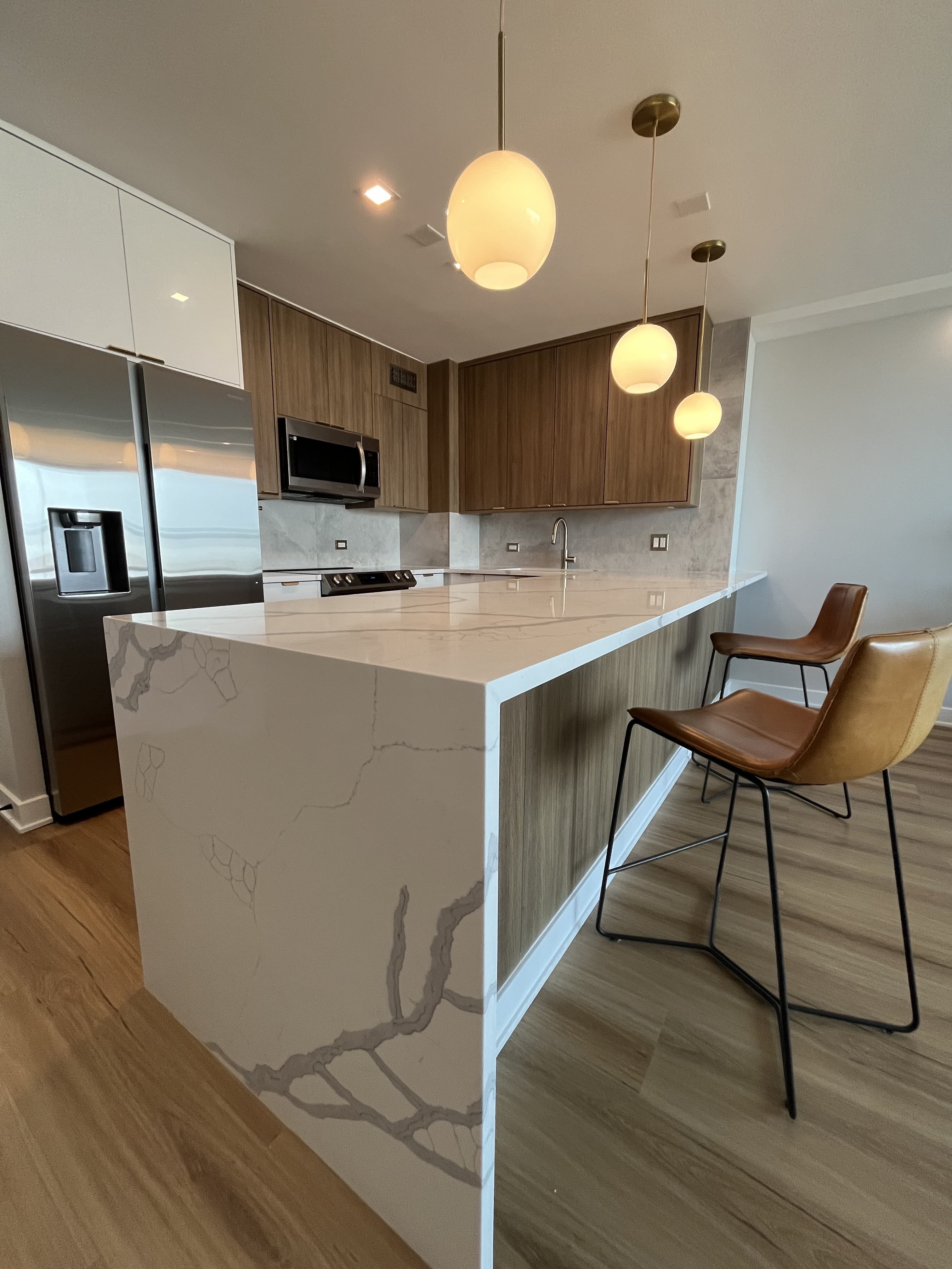 A renovated condo kitchen with a waterfall quartz island