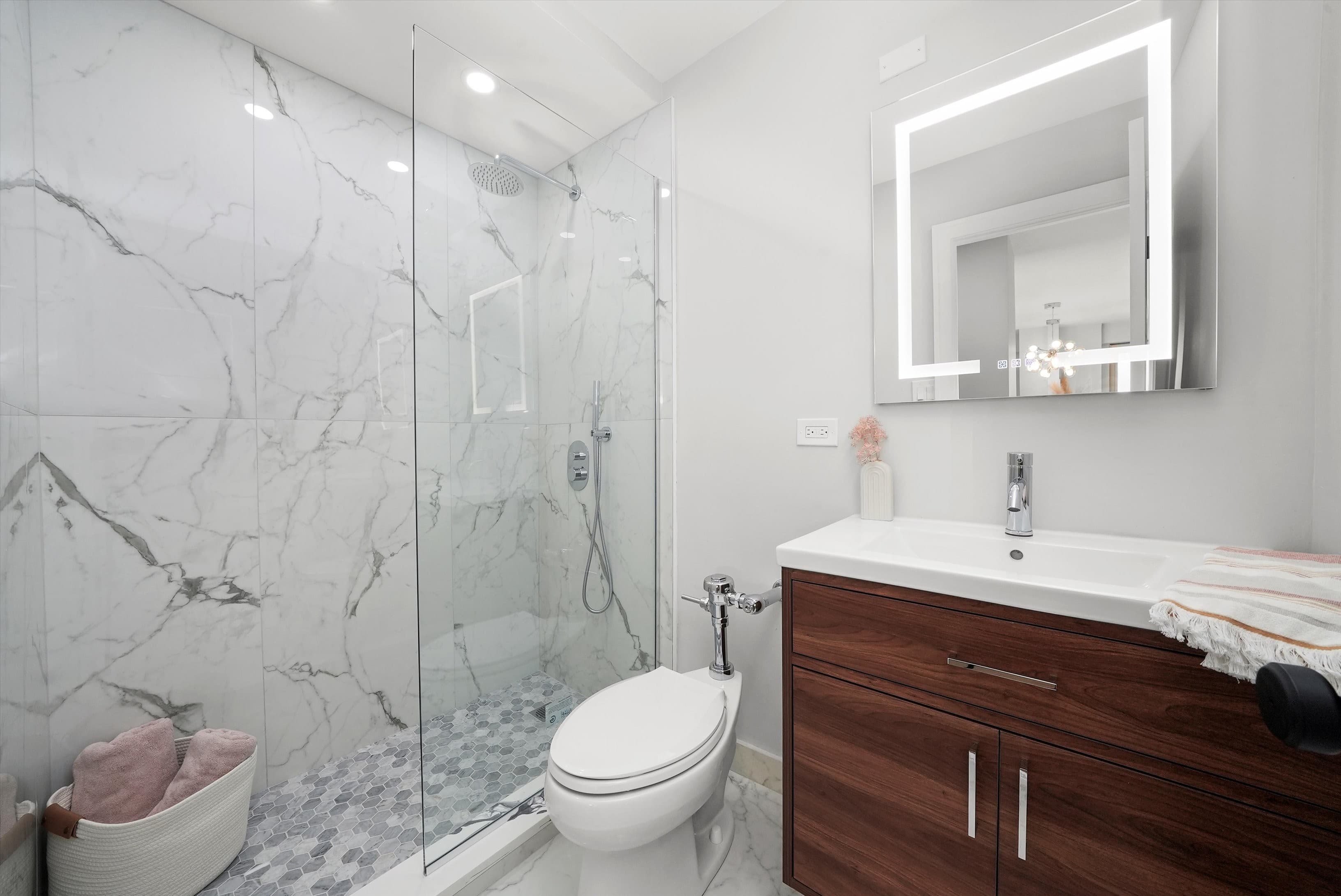 A renovated bathroom with a marble-slab walk-in shower