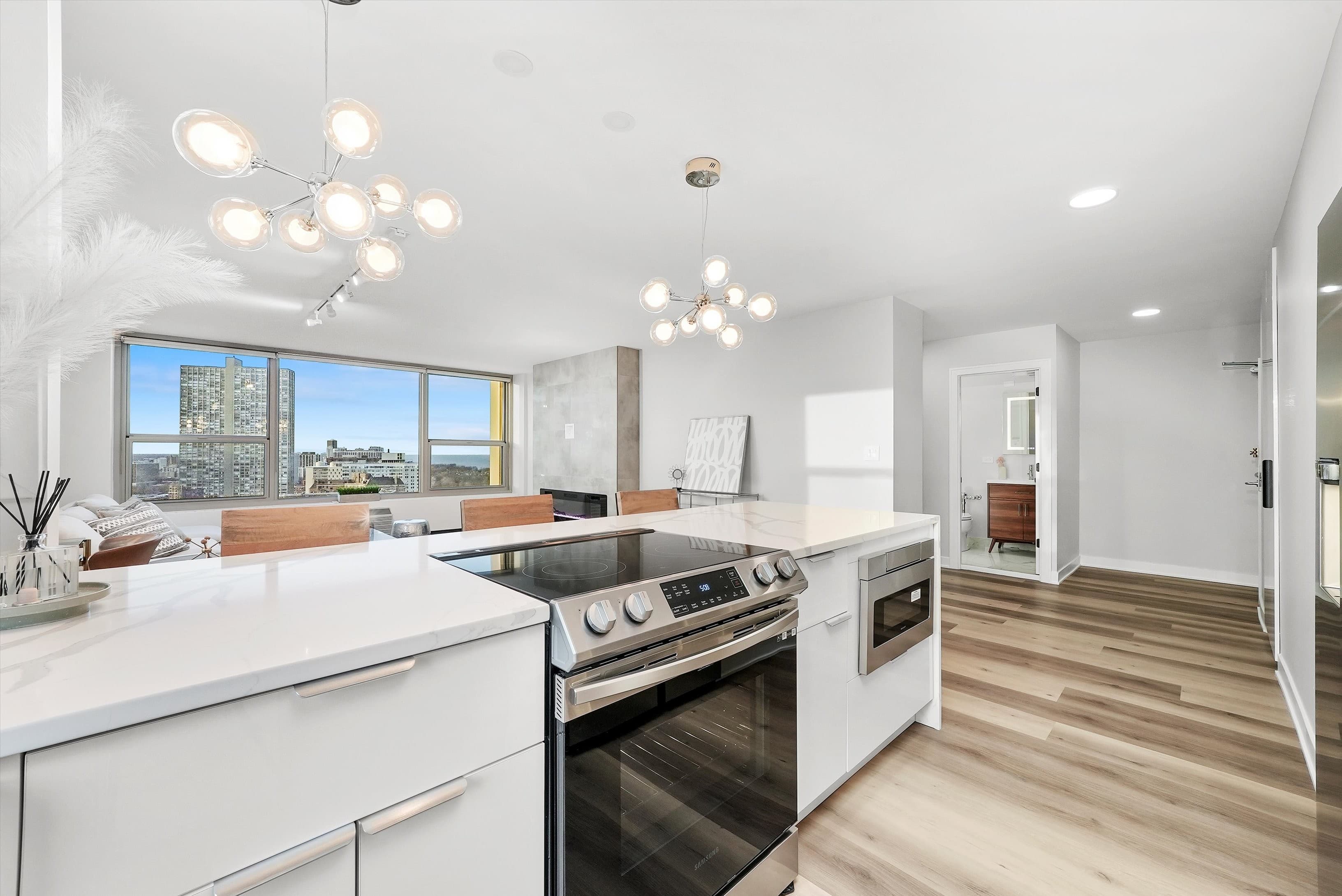 A bright kitchen with a city-skyline window view and sculptural chandelier