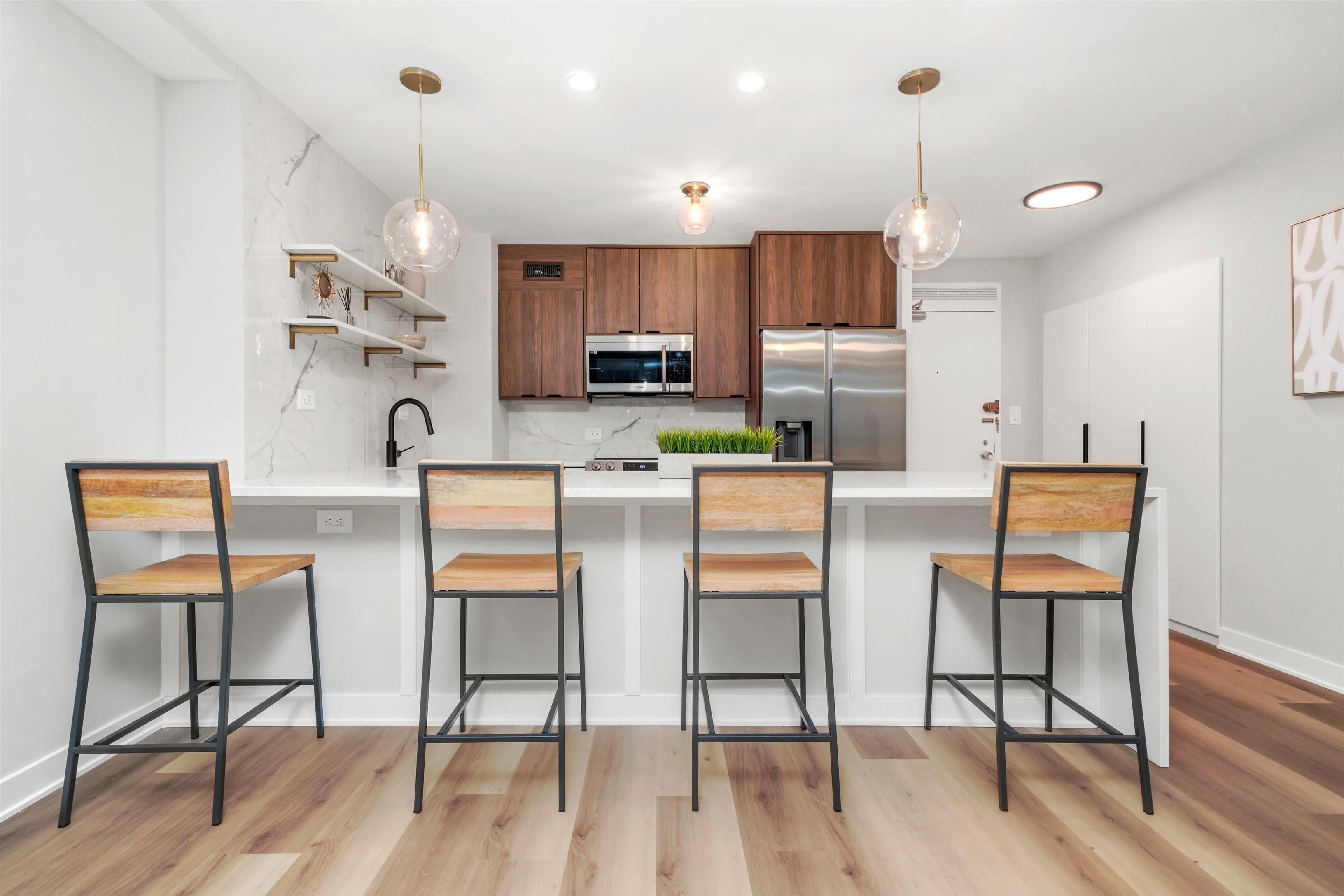 An editorial view of the waterfall island with four bar stools and marble backsplash