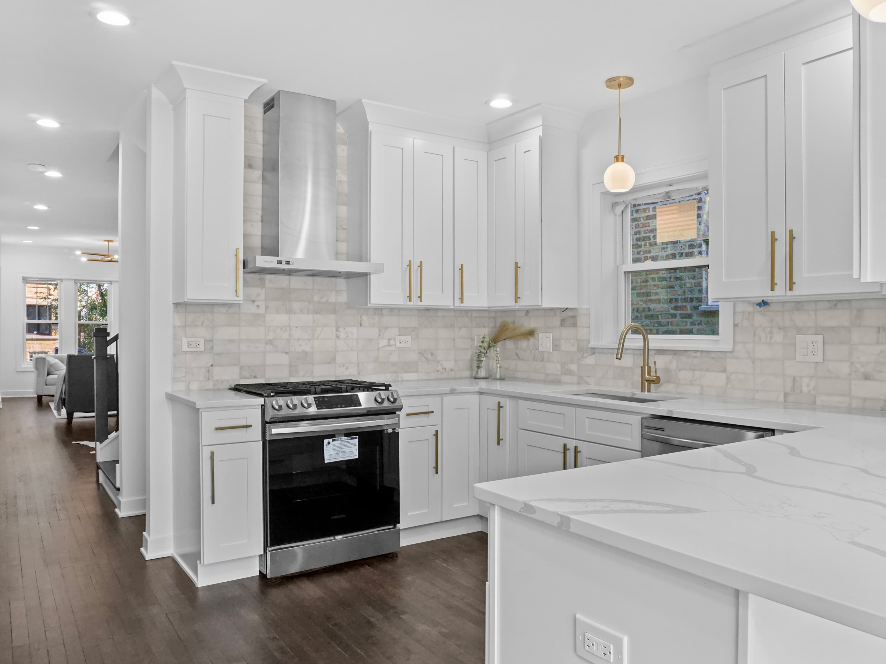 A bright white kitchen with shaker cabinets and brass lighting