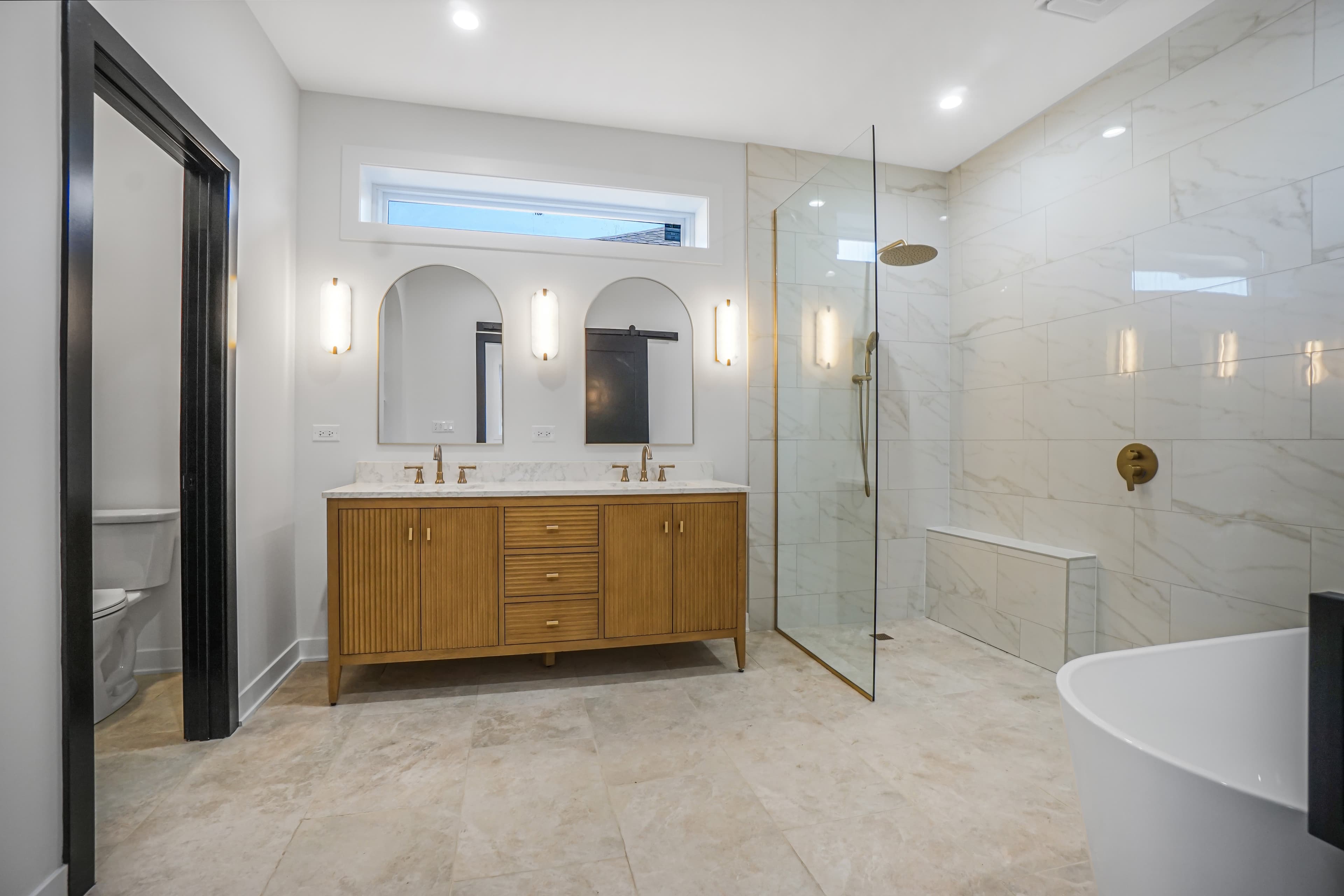 The double vanity with arched mirrors and glass walk-in shower