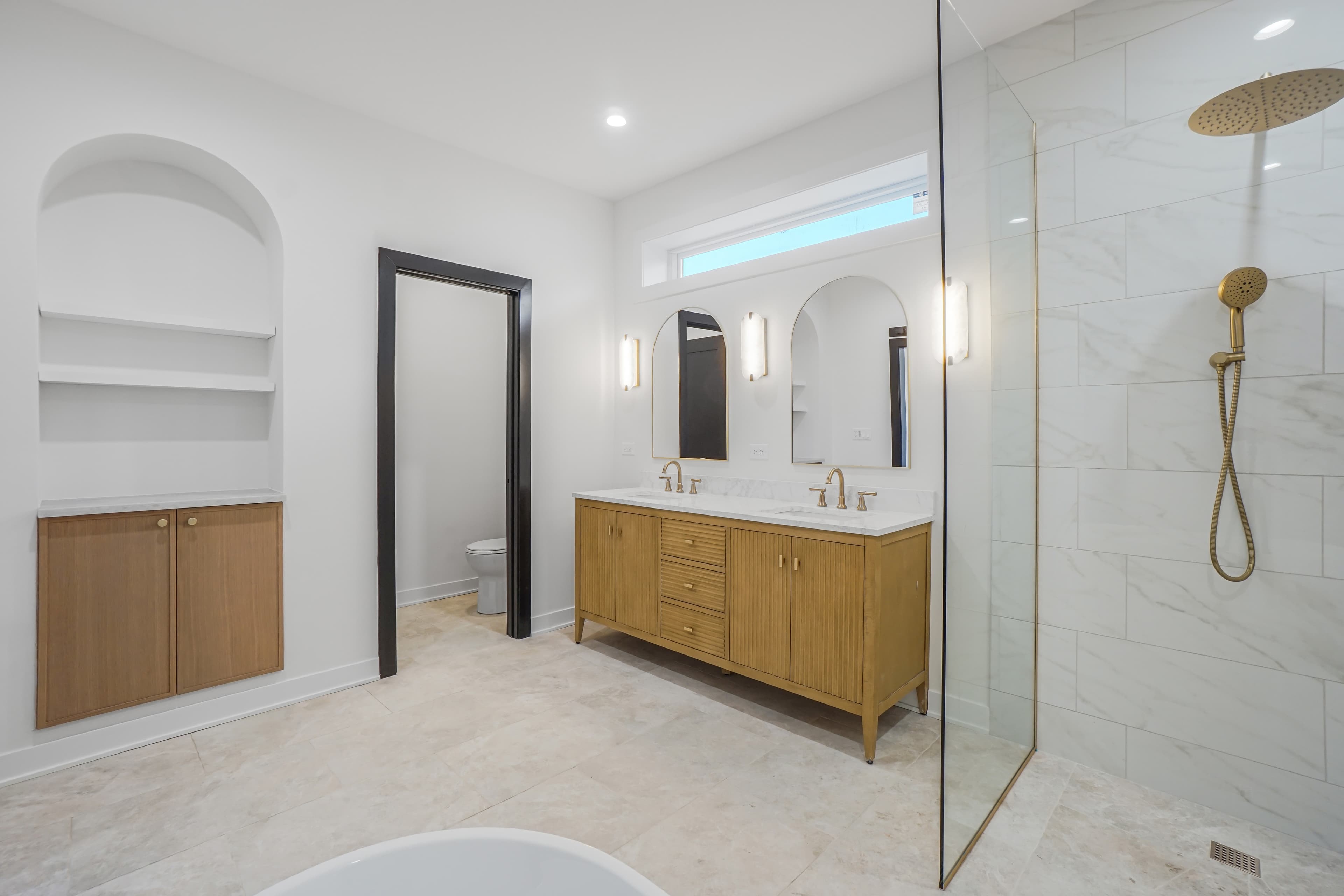 A view across the soaking tub toward the vanity and arched shelf nook