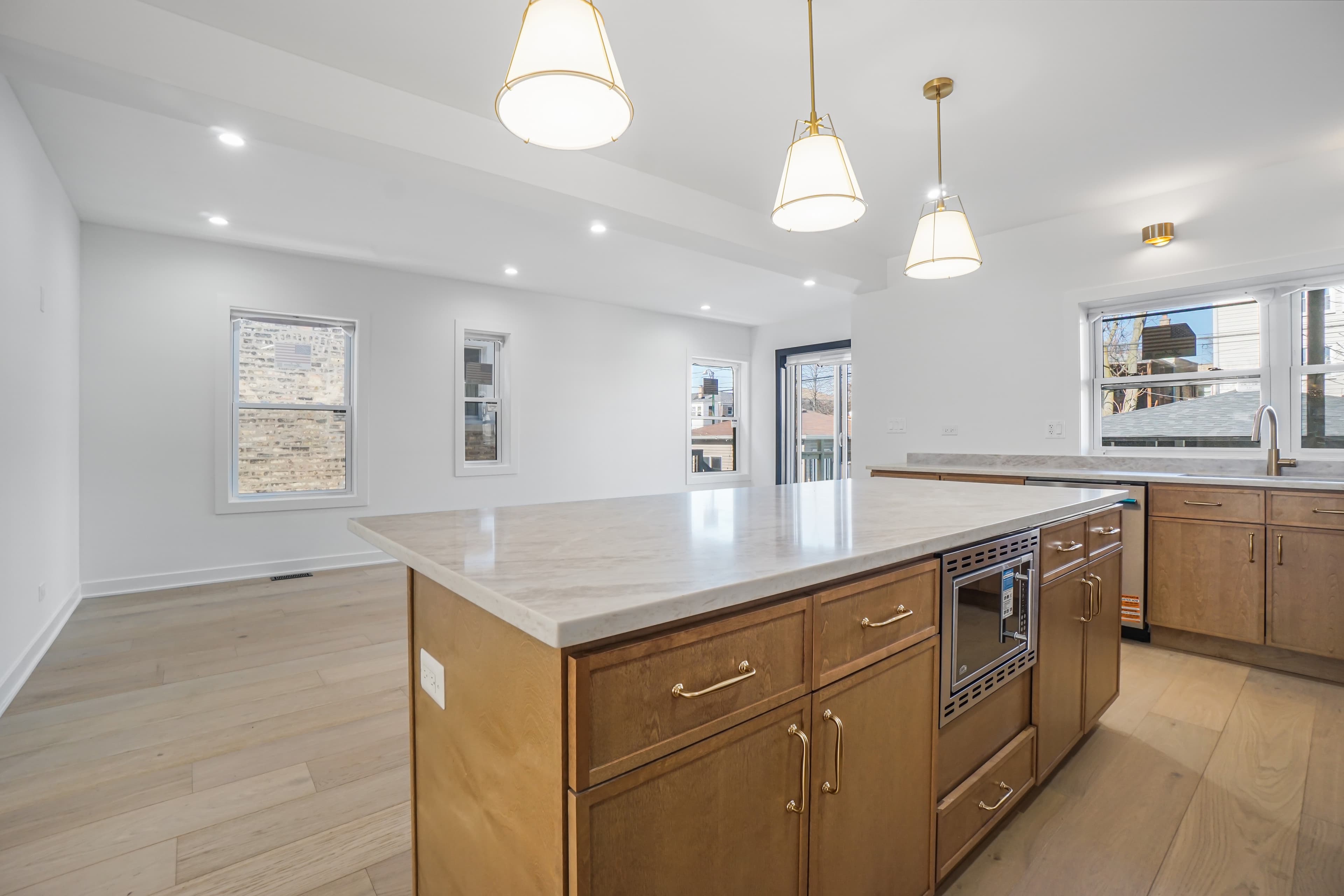 The kitchen island viewed toward the open dining area with brass pendant lighting