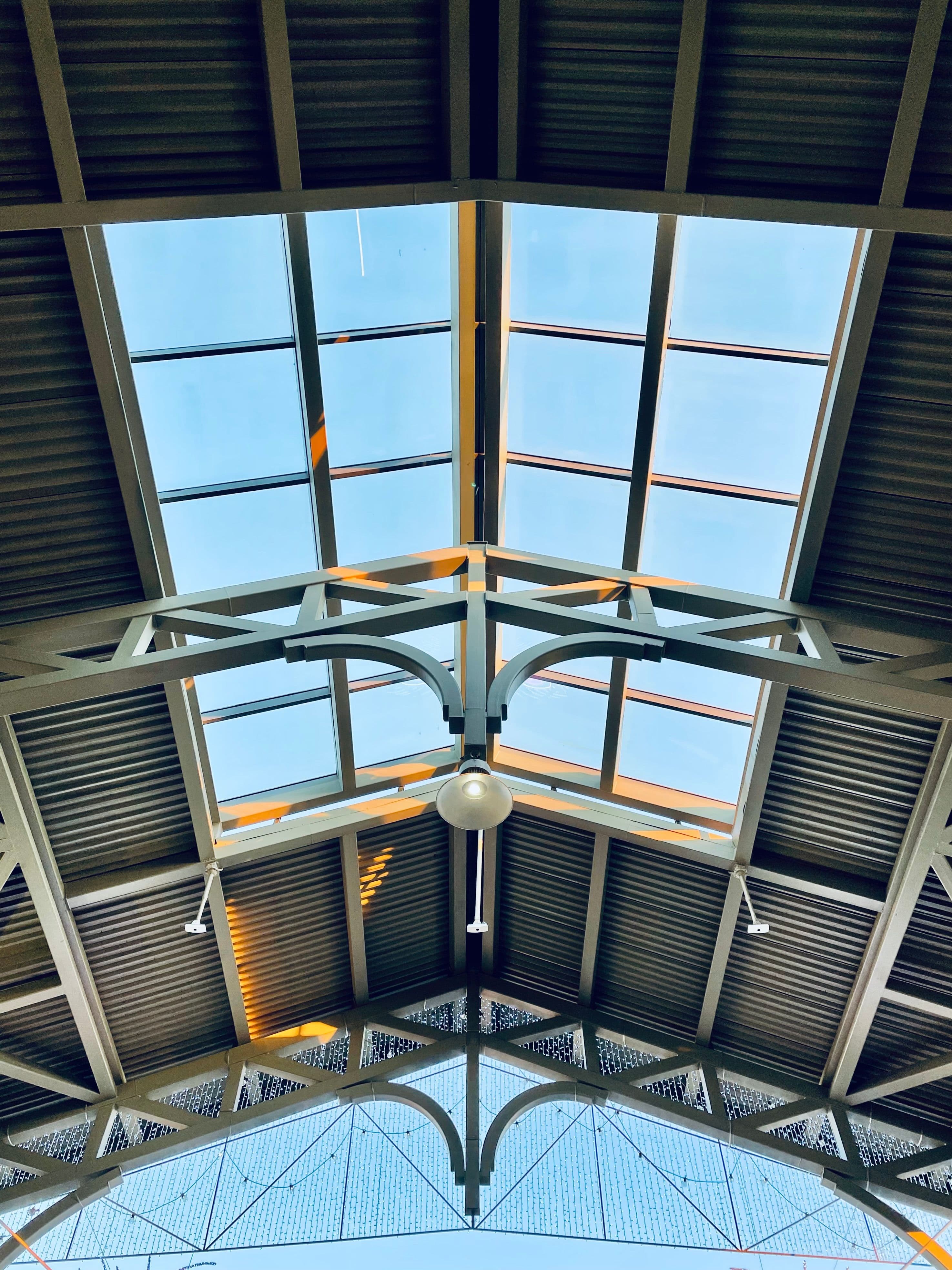 A steel-framed skylight viewed from below against a blue sky